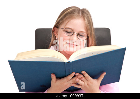 Mädchen, 8 Jahre, mit Brille, lesen in einem Buch Stockfoto