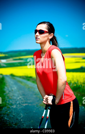 Junge Frau, die eine Pause beim Nordic walking Stockfoto