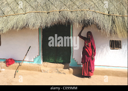 Frau in einen Sari am Eingang zu ihrem Haus mit genähten Reisig Dach, Thar-Wüste, Rajasthan, Nordindien, Indien, Asien Stockfoto