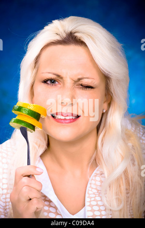 Junge Frau mit Scheiben von Zitrusfrüchten auf einer Gabel Stockfoto