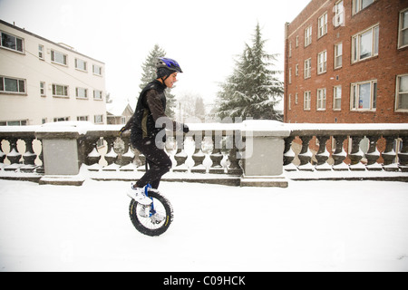 Ein Mann reitet auf seinem Einrad an einem verschneiten Tag in Seattle. Stockfoto