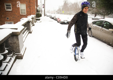 Ein Mann reitet auf seinem Einrad an einem verschneiten Tag in Seattle. Stockfoto