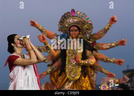 Frau bläst Muschelschale auf Durga puja Stockfoto