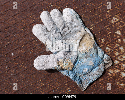 Stark abgenutzte Arbeitshandschuh auf rostigen Metallplatte Stockfoto