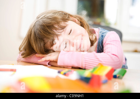 Ein Mädchen, ihren Kopf auf ihre Arme auf dem Tisch ruhen Stockfoto