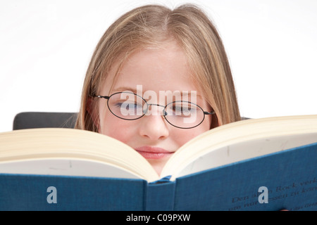 Mädchen, 8 Jahre, mit Brille, lesen in einem Buch Stockfoto