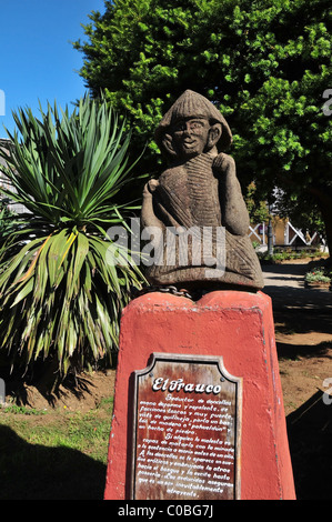 Braune Bildnis auf roten Sockel mit Informationstafel El Trauco mythische Monster, Plaza de Armas, Ancud, Chiloé Insel, Chile Stockfoto