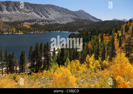 Einen schönen Bergsee mit türkis-blauem Wasser, umgeben von gelben und grünen Bäumen Stockfoto