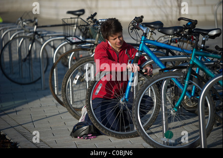 Eine junge weibliche Grad Student sperren Sie ihr Fahrrad in einem Bikepark auf dem Campus an der University of Exeter, Devon. Stockfoto