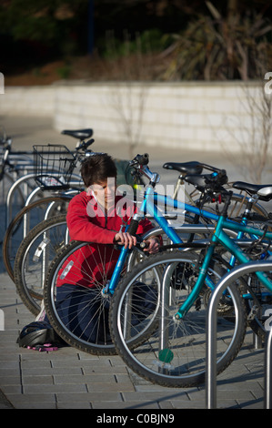 Eine junge weibliche Grad Student sperren Sie ihr Fahrrad in einem Bikepark auf dem Campus an der University of Exeter, Devon. Stockfoto