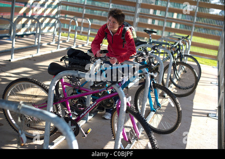 Eine weibliche Radfahrer sperren Sie ihr Fahrrad in einem Bikepark am University of Exeter, Devon Stockfoto