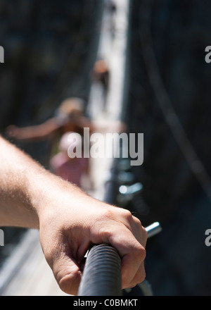 Mann hält auf Geländer auf der Hängebrücke Stockfoto
