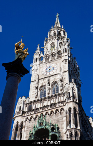 Niedrigen Winkel Blick auf das Münchner Rathaus (Rathaus) und eine Statue der Jungfrau Maria mit blauem Himmel Stockfoto