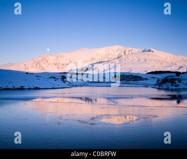 Winter-Mondaufgang über Snowdon und Llyn Y Dywarchen, Snowdonia-Nationalpark. Wales Stockfoto