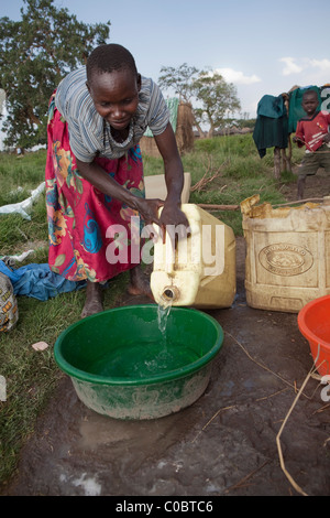 Eine Frau gießt Wasser aus einem Kanister in ländlichen Amuria District, Uganda, Ostafrika. Stockfoto