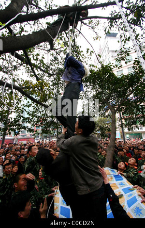 * Rettung Versuch Feuerwehrleute in China haben eine 70 Jahre alte Frau aus einem Baum gerettet.  Das "bellen" verrückten Rentner skaliert die Stockfoto