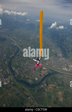 Mädchen Fallschirmspringer im freien Fall halten Sie eine orange Luftschlauch über grüne Felder. Stockfoto