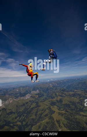 Fallschirmspringer sind Kopf fliegen innerhalb eines Teams in der Sit-fliegen-Position über eine spektakuläre Bergkulisse. Stockfoto