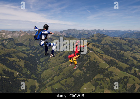 Fallschirmspringer sind Kopf fliegen innerhalb eines Teams in der Sit-fliegen-Position über eine spektakuläre Bergkulisse. Stockfoto