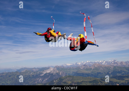 Fallschirmspringer sind Kopf fliegen innerhalb eines Teams in der Sit-fliegen-Position über eine spektakuläre Bergkulisse. Stockfoto