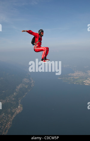 Fallschirmspringer ist sitzen mit einem Lächeln über einem See und schönen Landschaft fliegen. Stockfoto