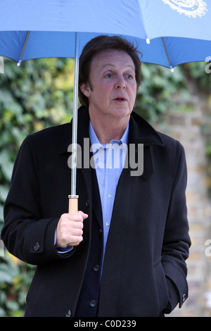 Sir Paul McCartney stellt für Fotografen, als er nach Hause im Regen geht, geschützt von einem großen blauen Schirm London, England- Stockfoto