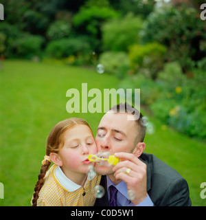 Vater und Tochter Seifenblasen im Garten Stockfoto