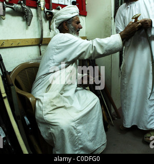 Ein omanischer Mann sitzt in einem Waffen-Shop in der indoor Souk (Markt) von Nizwa, Oman. Stockfoto