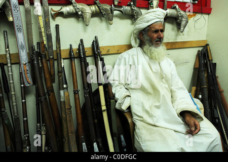 Ein omanischer Mann sitzt in einem Waffen-Shop in der indoor Souk (Markt) von Nizwa, Oman. Stockfoto