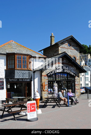 Touristen, die entspannende außerhalb der alten Rettungsstation in Looe in Cornwall, Großbritannien Stockfoto