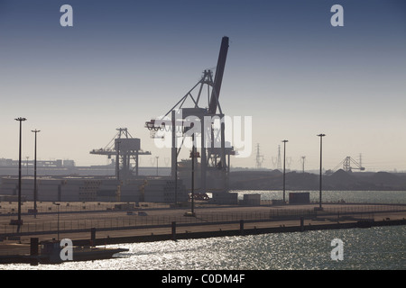 Krane und Container auf einem modernen dock Terminal mit älteren Anlagen der Schwerindustrie im Hintergrund Stockfoto