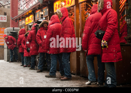 Snack-Hersteller warten im eisigen Bedingungen für Kunden in Wang Fu Jing Lebensmittelmarkt, Peking, China Stockfoto