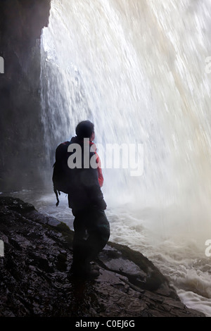 Weibliche Walker mit wasserdichter Kleidung hinter Sgwd Gwladus Wasserfall auf die Wasserfälle zu Fuß Powys Wales UK Stockfoto