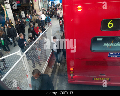 Shopper Fußgänger zu Fuß auf der Straße zwischen einem Doppeldecker-Bus und eine Crossrail Barriere Oxford Street London England UK Stockfoto