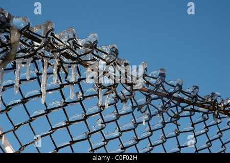 Nahaufnahme von Eiszapfen hängen von net Zaun Stockfoto