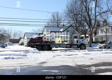 Zerschmetterte rotes Auto auf Abschleppwagen mit Krankenwagen und Polizei-Kreuzer Stockfoto