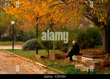 Ein einsamer alter Mann sitzen skeptisch und melancholisch auf einer Bank auf der Uferstraße von Ioannina, Epirus, Griechenland Stockfoto