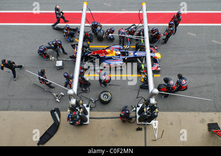 Deutsche Formel1-Fahrer Sebastian Vettel und Red Bull Pitcrew üben einen Boxenstopp mit der RB7 Rennwagen im Februar 2011 Stockfoto