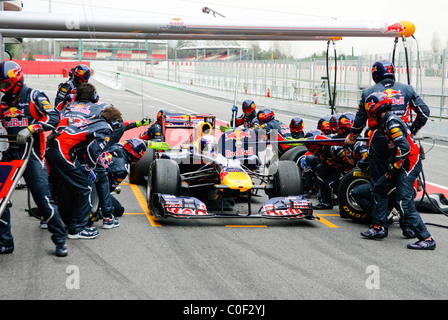 Deutsche Formel1-Fahrer Sebastian Vettel und Red Bull Pitcrew üben einen Boxenstopp mit der RB7 Rennwagen im Februar 2011 Stockfoto