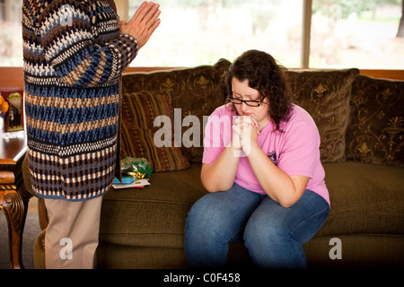Reedley, California, Vereinigte Staaten von Amerika.  Ein übergewichtiger Teenager-Mädchen betet mit Kaplan auf einer Couch. Stockfoto