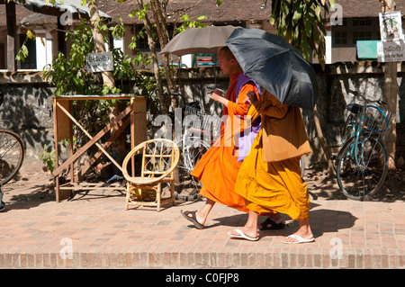 Zwei buddhistische Mönche halten Sonnenschirme schlendern Sie entlang einer Straße in Luang Prabang Laos Stockfoto