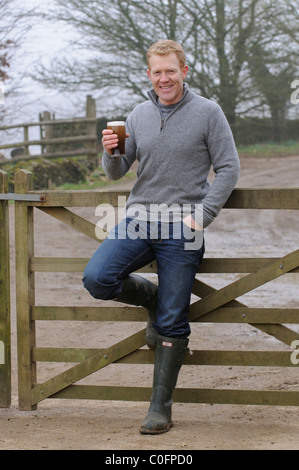 Halten ein Glas Bier Adam Henson Landwirt und TV-Moderatorin zu Hause auf seinem Hof Gloucestershire in den Cotswolds-England Stockfoto