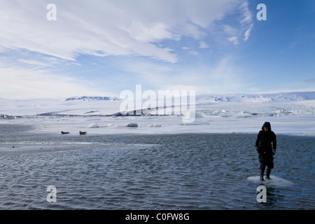 Eine Frau steht auf einen kleinen Bruchteil der Eisberg in der Gletscherlagune Jökulsárlón in Island. Stockfoto