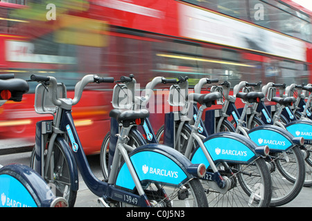 Ein Bus, vorbei an einer Reihe von Boris Bikes in ihren Gestellen Stockfoto