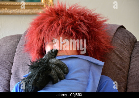 Ein älterer Mann wirkt dumm, indem sie auf einem roten fuzzy Perücke. USA. Stockfoto