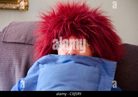 Ein älterer Mann wirkt dumm, indem sie auf einem roten fuzzy Perücke. USA Stockfoto