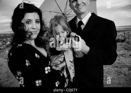 Familie mit drei posieren für ein Familienporträt in der Wüstenlandschaft mit einem grünen Dach. Stockfoto