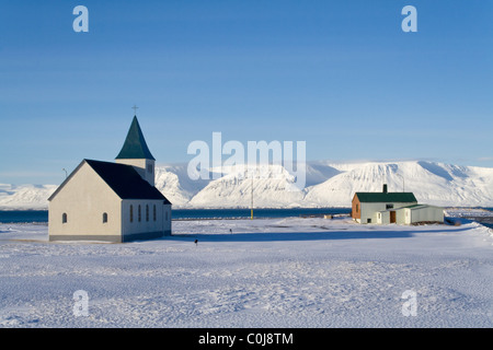 Die Kirche in Hofsos, Island, und ein kleines Haus.  Tindastoll Berg ist auf der anderen Seite des Fjords Skagafjördur. Stockfoto