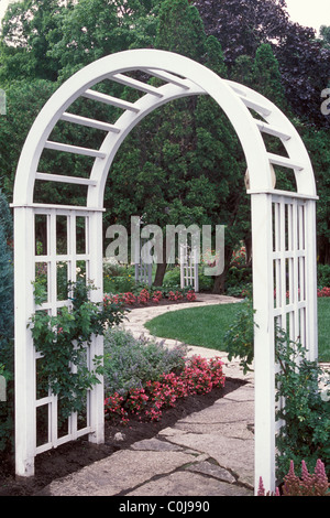 WEIßE HOLZ ARBOR FRAMES STEIN WEG IN MINNESOTA GARTEN.  BEGONIEN UND KATZENKRAUT GRENZE WEG; KLETTERN AM ARBOR GESTIEGEN. SOMMER. Stockfoto