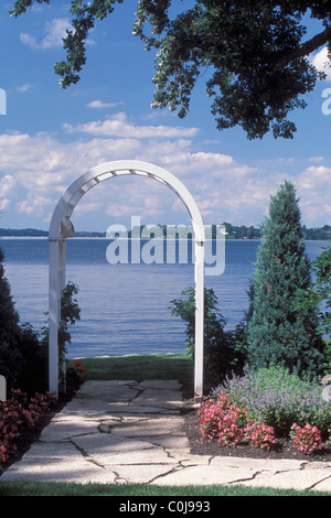 WEIßE HOLZ ARBOR FRAMES STEIN WEG IN MINNESOTA SEEGARTEN. BEGONIEN UND KATZENMINZE NEPETA LINIE WEG.  SOMMER. Stockfoto